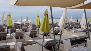 A beachside seating area with wooden loungers and umbrellas, overlooking the sea. - Very bright villa standing 5 minutes walk from the beach  (Le Grau-du-Roi)