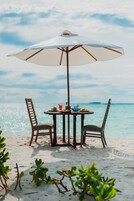 Na praia, areia branca, espreguiçadeiras, guarda-sóis 