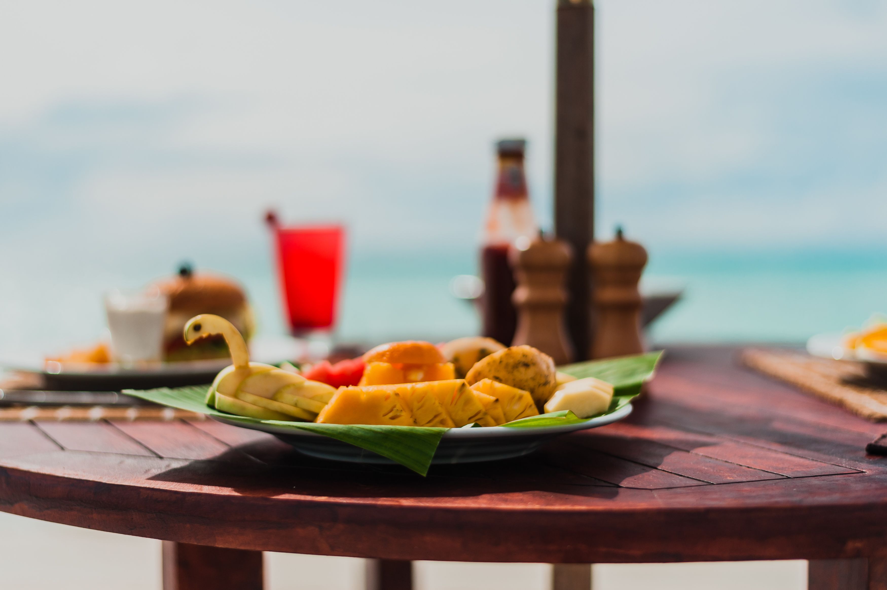 Una mesa con un plato de fruta y una botella de bebida, sobre un fondo desenfocado.