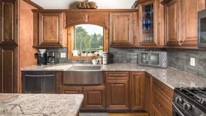 A kitchen with wooden cabinets, granite countertops, a stainless steel sink, a stove, and a microwave. - Upscale Home near Blue Ridge Parkway (Boone)