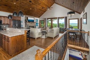 A spacious kitchen with wooden cabinets, a granite countertop, and a dining area with a view.