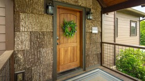A wooden door with a wreath, a stone wall, and a balcony with a railing. - Upscale Home near Blue Ridge Parkway (Boone)