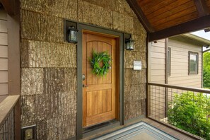 A wooden door with a wreath, a stone wall, and a balcony with a railing.