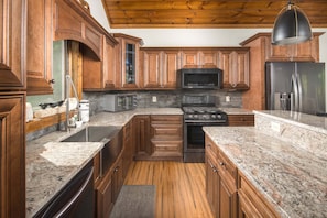 A kitchen with wooden cabinets, granite countertops, a stainless steel refrigerator, a microwave, and a stove. - Upscale Home near Blue Ridge Parkway (Boone)