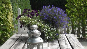 Una mesa de madera con un farol y arreglos florales.