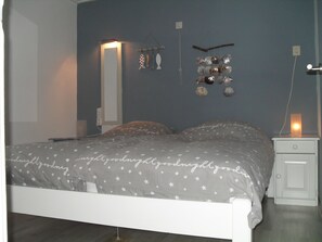 A bedroom with a bed, nightstand, wall decorations, and a wall-mounted light.