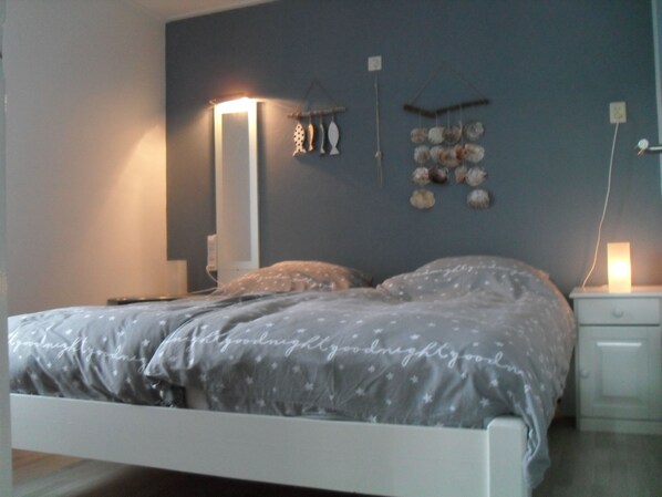 Een slaapkamer met een bed, nachtkastjes, een wandplank en decoratieve objecten.