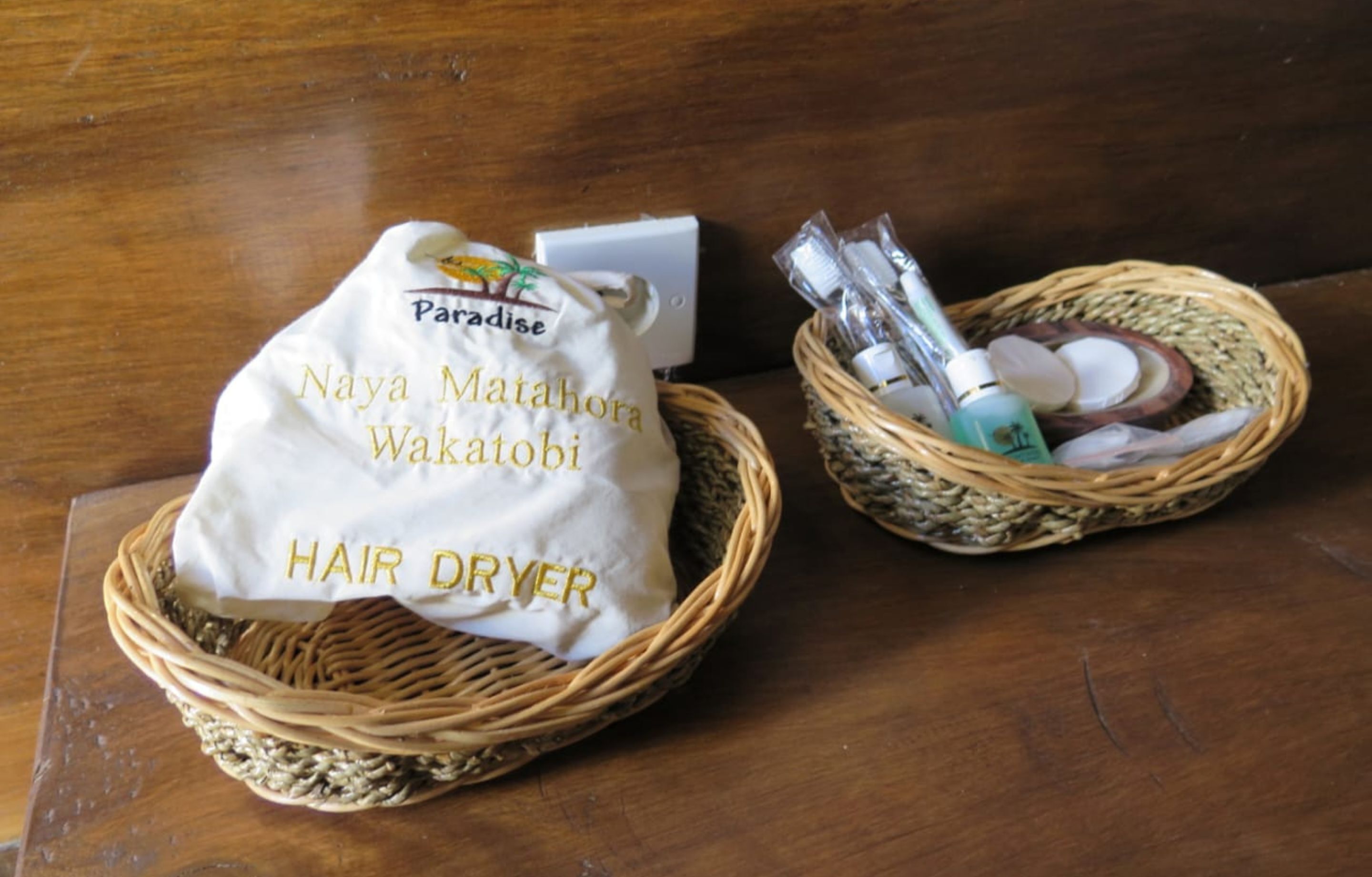 Two wicker baskets containing hair care products and a white cloth bag with text.