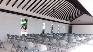 Une grande salle avec des rangées de chaises et un plafond élevé orné de poutres en bois.