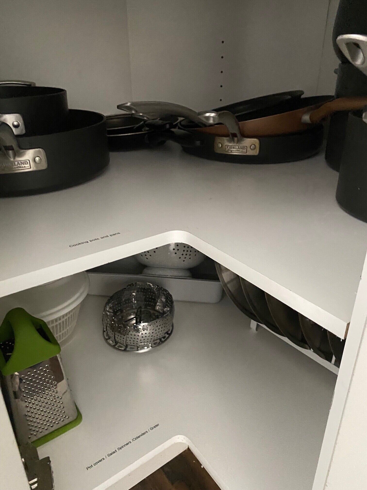 Et køkken med en hvid bordplade, en sigte, en rivejern og en metal gryde.