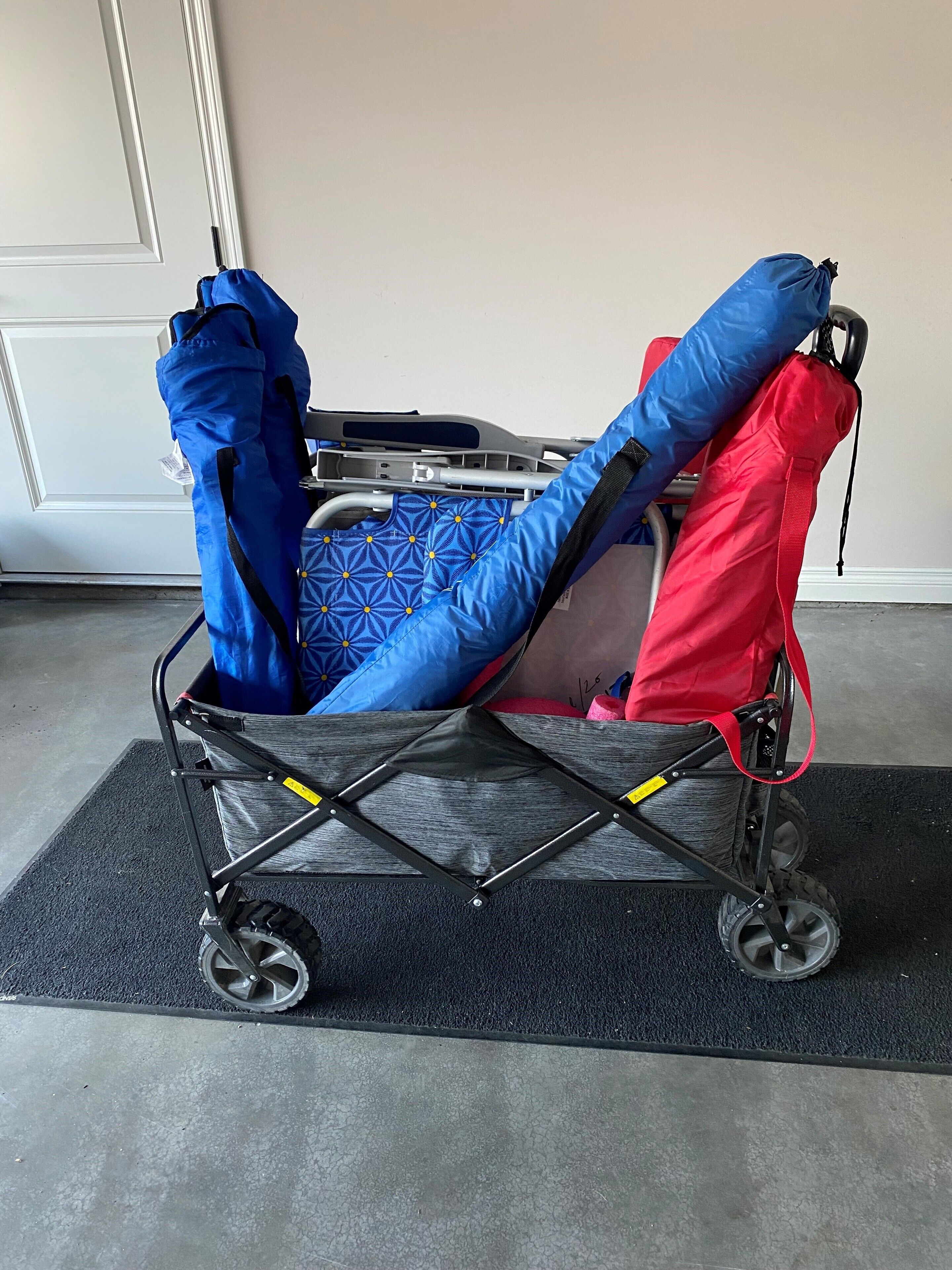 A stroller with a black frame and wheels, a blue and red seat, and a patterned cushion.