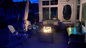 Une terrasse avec des meubles d’extérieur, un foyer et une fenêtre agrémentée d’éléments décoratifs.