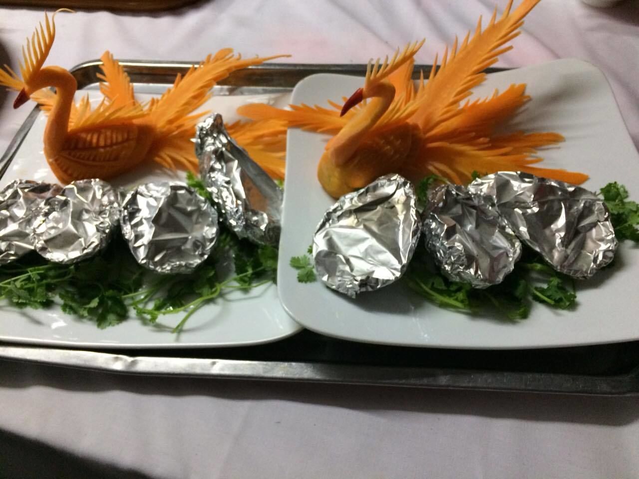 Two plates with swan-shaped food decorations and foil-wrapped items on a tray.