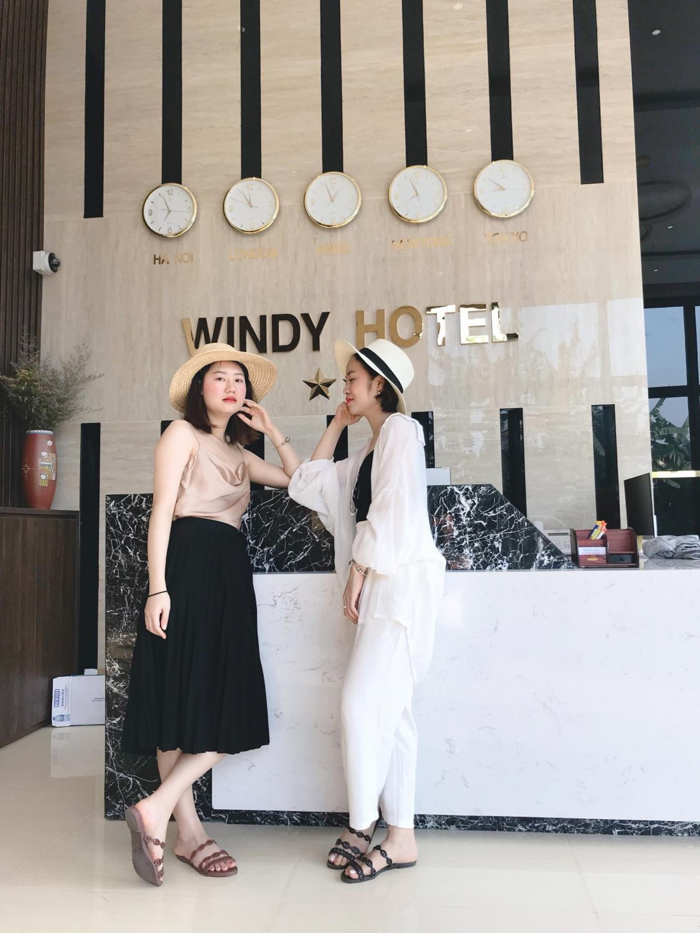 A reception desk at Windy Hotel with a modern design, featuring a marble countertop and a wall clock.