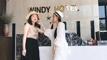 A reception desk at Windy Hotel with a modern design, featuring a marble countertop and a wall clock.