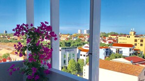 A balcony with a potted plant and a view of a cityscape.