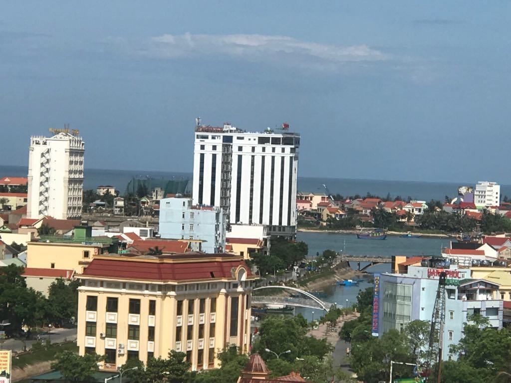 A cityscape with a prominent white building with vertical stripes, a yellow building with columns, and a river in the background.