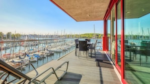 Ein Balkon mit Blick auf eine Marina, mit Booten und einer entfernten grünen Landschaft.
