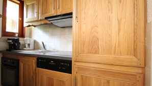 A kitchen with wooden cabinets, a Bosch dishwasher, a coffee maker, and a window with blinds. - Apartment for 6 in Val Cenis Lanslevillard, includes parking (Lanslevillard)