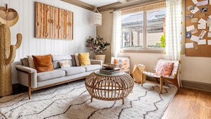 Una sala de estar acogedora con un sofá, una mesa redonda de centro, una silla y un ventanal con vistas al exterior.