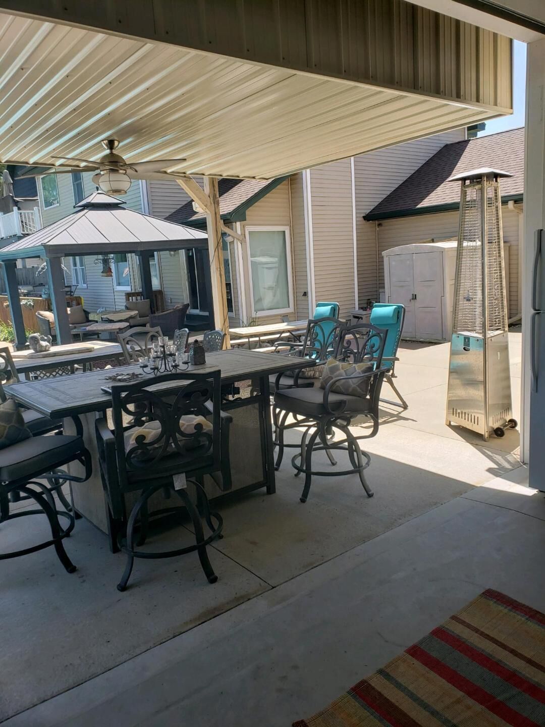 An outdoor patio area with a covered seating arrangement, a table with chairs, and a decorative lantern.