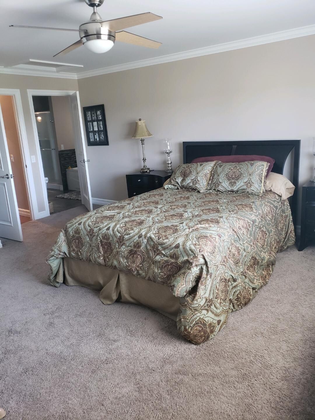Quarto com cama, ventoinha no teto, mesa de cabeceira e quadro na parede.