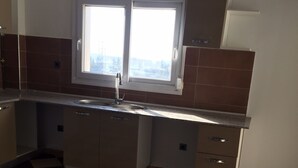 A kitchen with a checkered floor, two windows, and cabinets. - Apartment in a private residence with caretaker (Souidania)