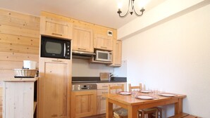 Una cocina compacta con armarios de madera, un microondas, un horno y una mesa de comedor con bancos.