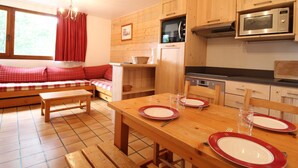 Una cocina acogedora con armarios de madera, una mesa de comedor para cuatro personas y un sofá rojo a cuadros.