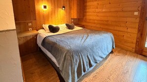 A wooden-paneled room with a bed, two wall-mounted lights, and a wooden floor.