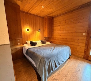 A wooden-paneled room with a bed, two wall-mounted lights, and a wooden floor.
