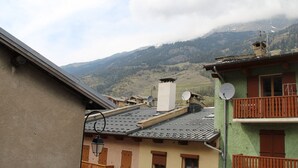 Un bâtiment traditionnel doté d’un balcon, d’une antenne parabolique et offrant une vue sur un paysage montagneux.