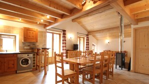 Une cuisine spacieuse dotée de meubles en bois, d’un lave-linge encastré et d’un coin repas avec des tables et des chaises en bois.