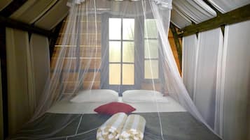 A room with a bed under a canopy, a window, and a view of the outside.