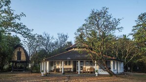A single-story house with a tiled roof, surrounded by trees and a clear sky. - Moon Isle Beach Bunglow (Nilaveli)