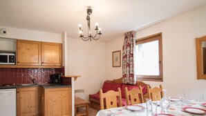Une cuisine avec des meubles en bois, un four à micro-ondes et un coin repas avec une table dressée pour quatre personnes.