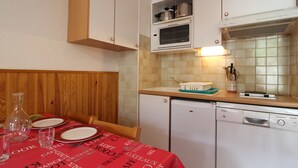 A compact kitchen with white cabinets, a built-in oven, and a dishwasher.