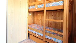 A wooden bunk bed room with two beds, each with patterned bedding.