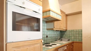 A kitchen with wooden cabinets, a white stove, and a green tiled backsplash. - Spacious apartment 5 ppl with balcony and wifi in Lanslebourg (Lanslebourg-Mont-Cenis)
