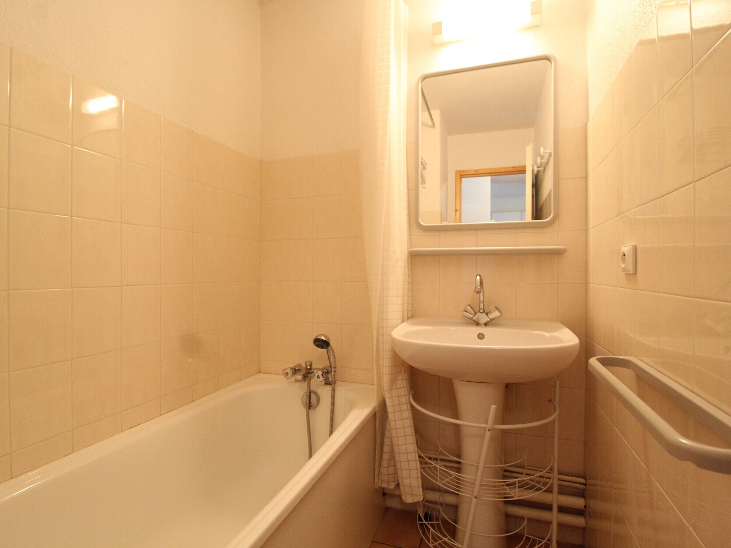 A bathroom with a bathtub, a sink, and a mirror.