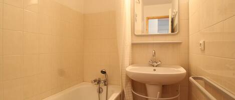 A bathroom with a bathtub, a sink, and a mirror.