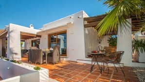 Une terrasse avec des meubles d’extérieur, une pergola et un palmier.