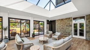 A spacious indoor area with wicker furniture, large windows, and a stone wall. - Victorian Mansion, fully refurbished, sleeps 24 guests in 12  ensuite bedrooms (Carnoustie)