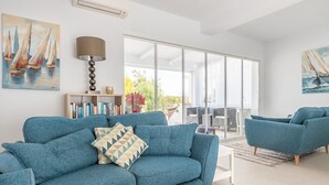 A modern living room with a blue sofa, a matching armchair, and a bookshelf. - Villa LADERA by Abahana Villas (Calp)