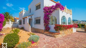A white villa with a stone-paved entrance, arched windows, and vibrant bougainvillea vines. - Villa LADERA by Abahana Villas (Calp)