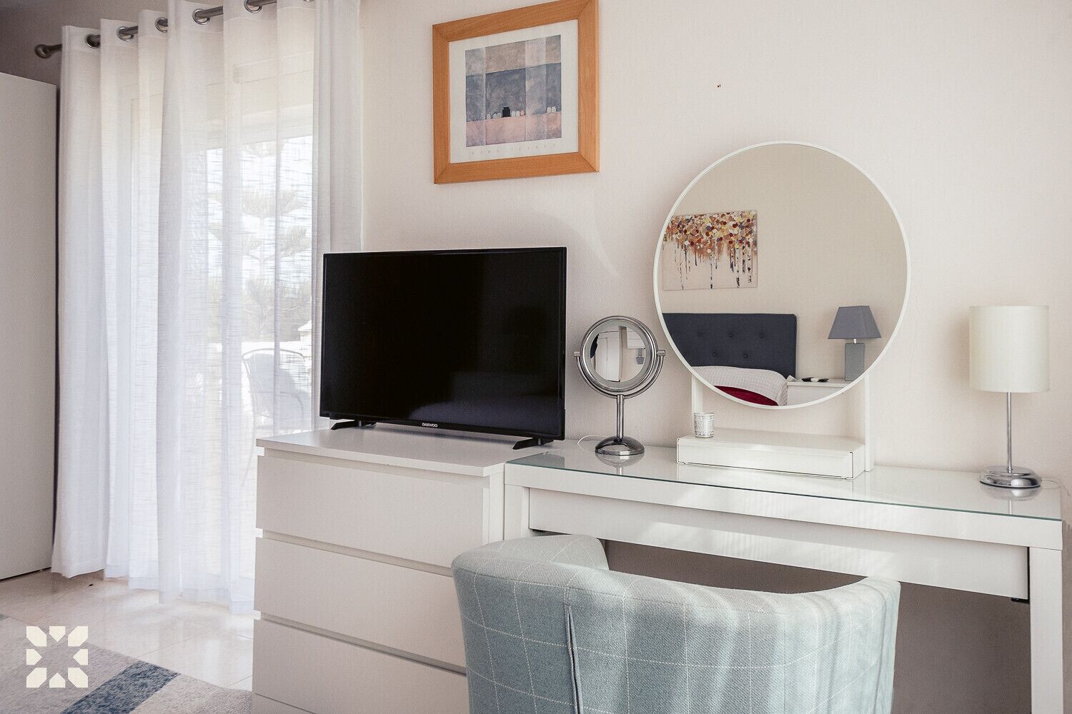A modern bedroom with a TV, a round mirror, a bedside table, and a lamp.
