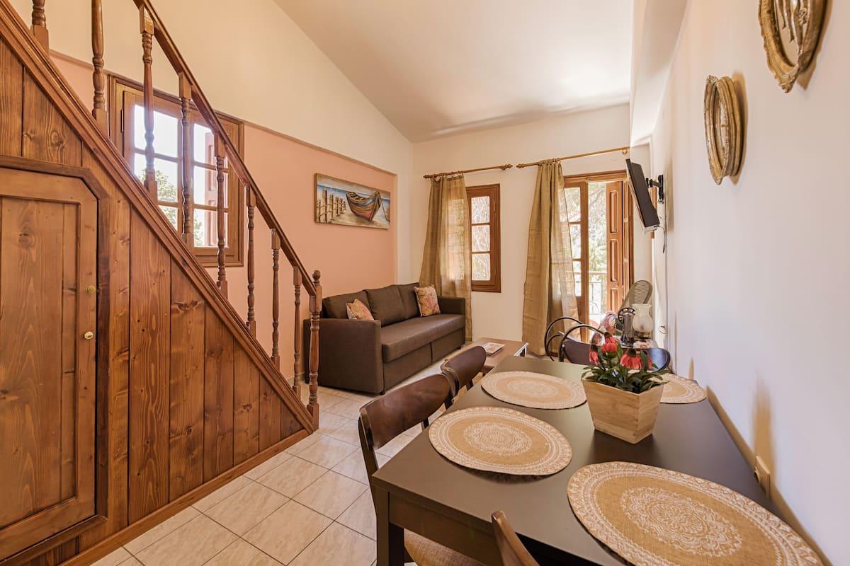 Un coin repas avec un escalier en bois, un canapé et une table agrémentée de sets de table.