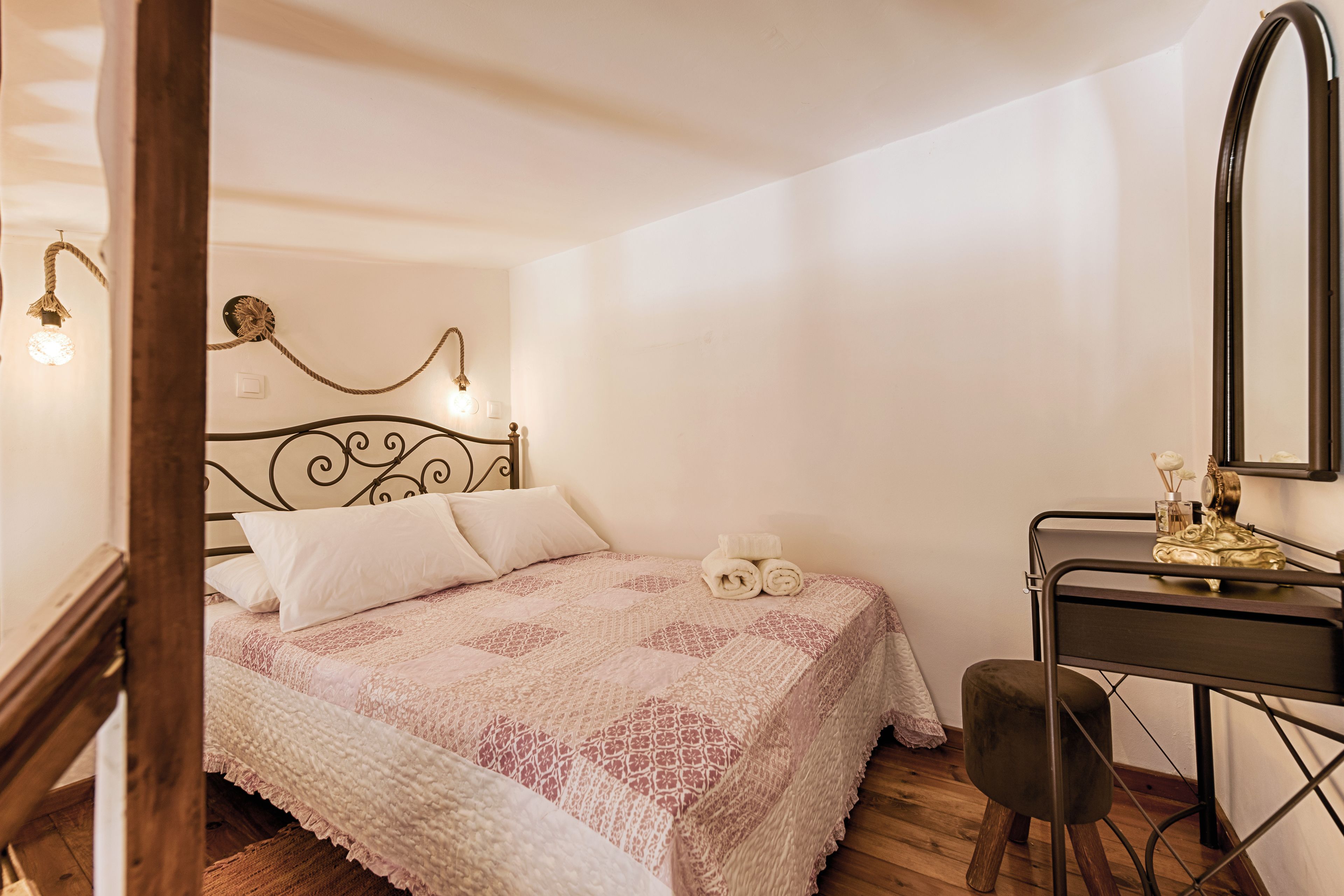 Een slaapkamer met een bed, een bureau en een spiegel.