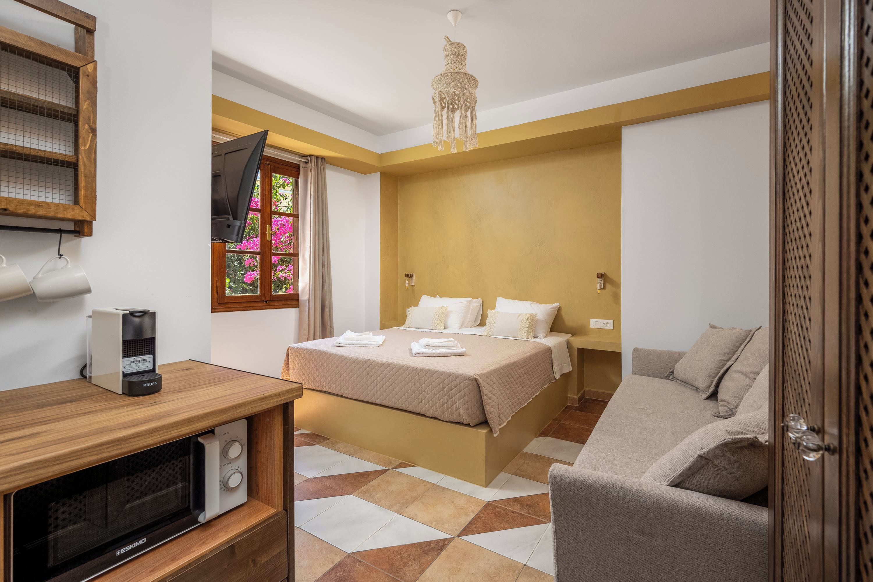 Une chambre d’hôtel équipée d’un lit, d’un canapé, d’une télévision, d’une machine à café et d’un four à micro-ondes.