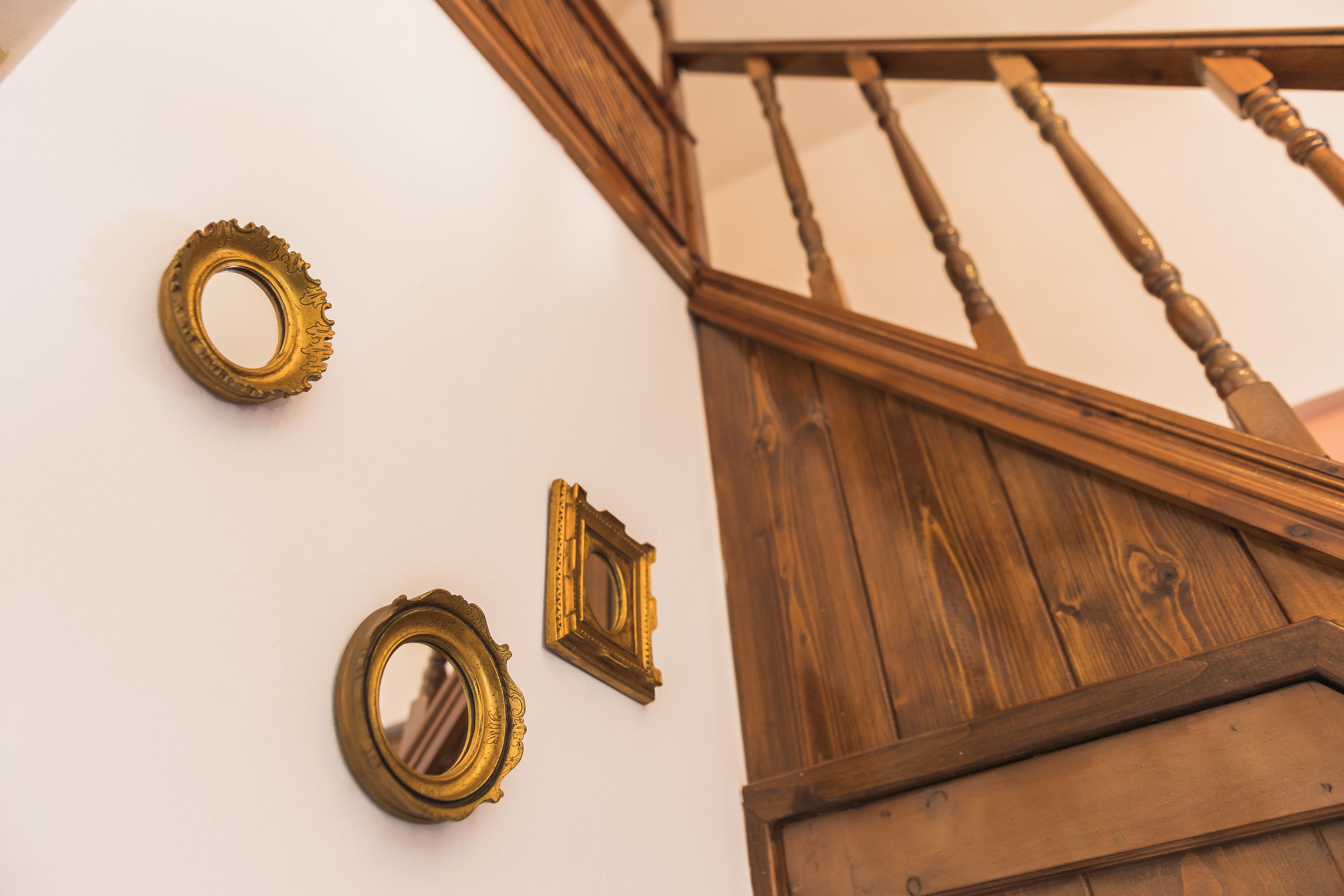 A staircase with wooden railings and three wall-mounted mirrors.